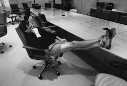 Steve leans back on his chair in a conference room. He is wearing shorts, legs stretched out and feet on the table.