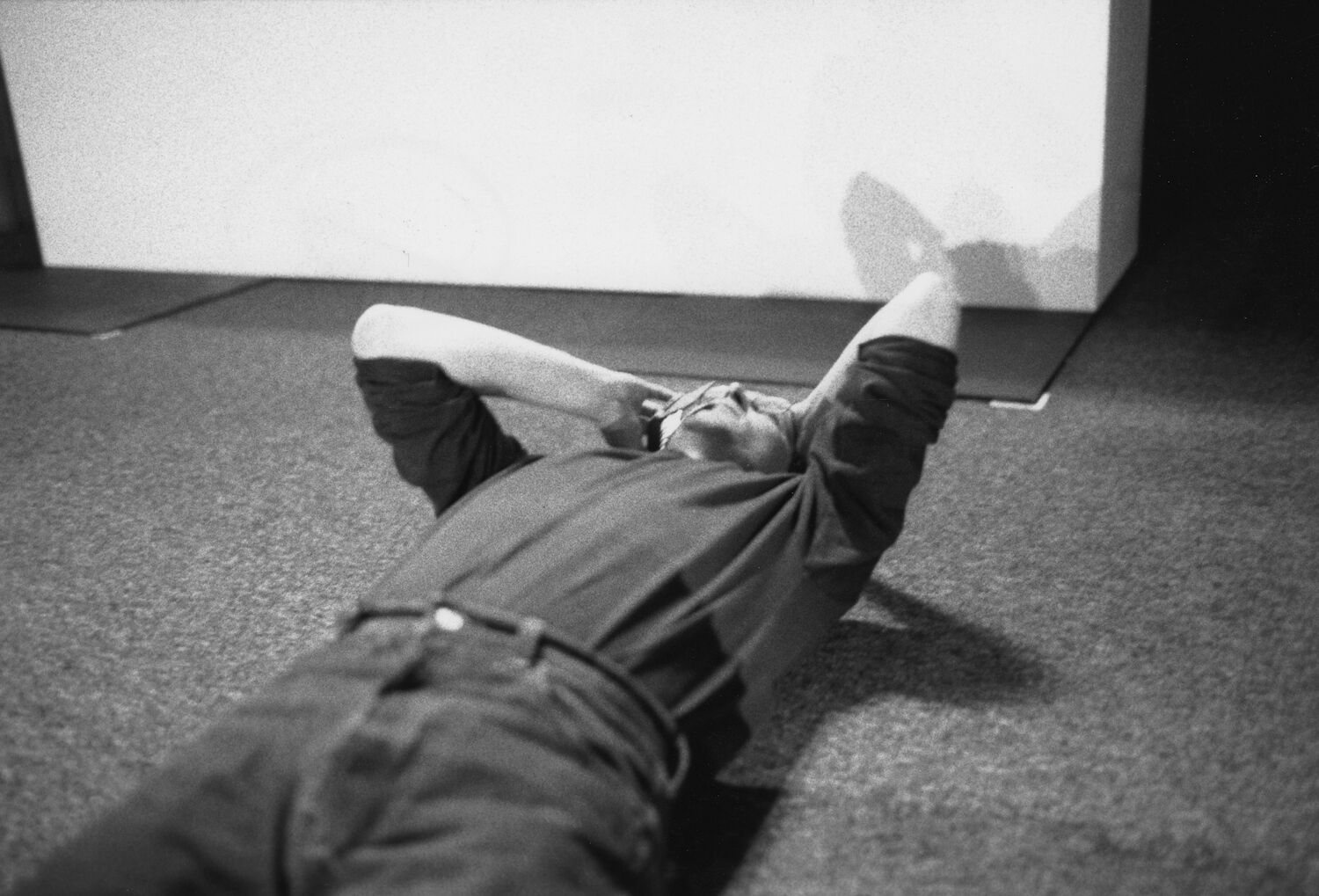 Steve lies on his back on a carpeted floor, talking on a cellphone and looking at the ceiling with his hand on his head.